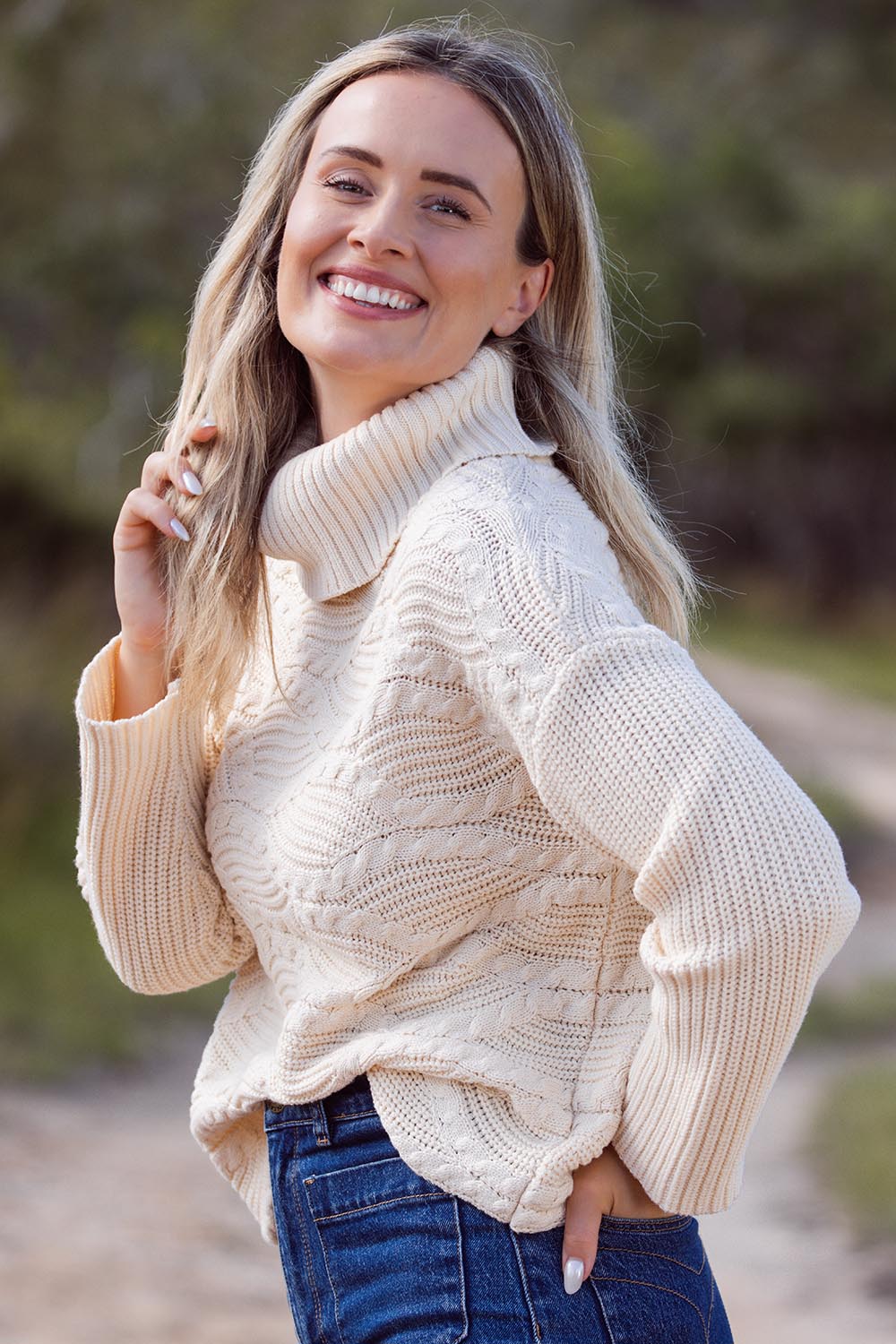 A model wearing the Wave Knit Roll Neck Cotton Blend Sweater in colour Vanilla, from the front, showing the whole outfit