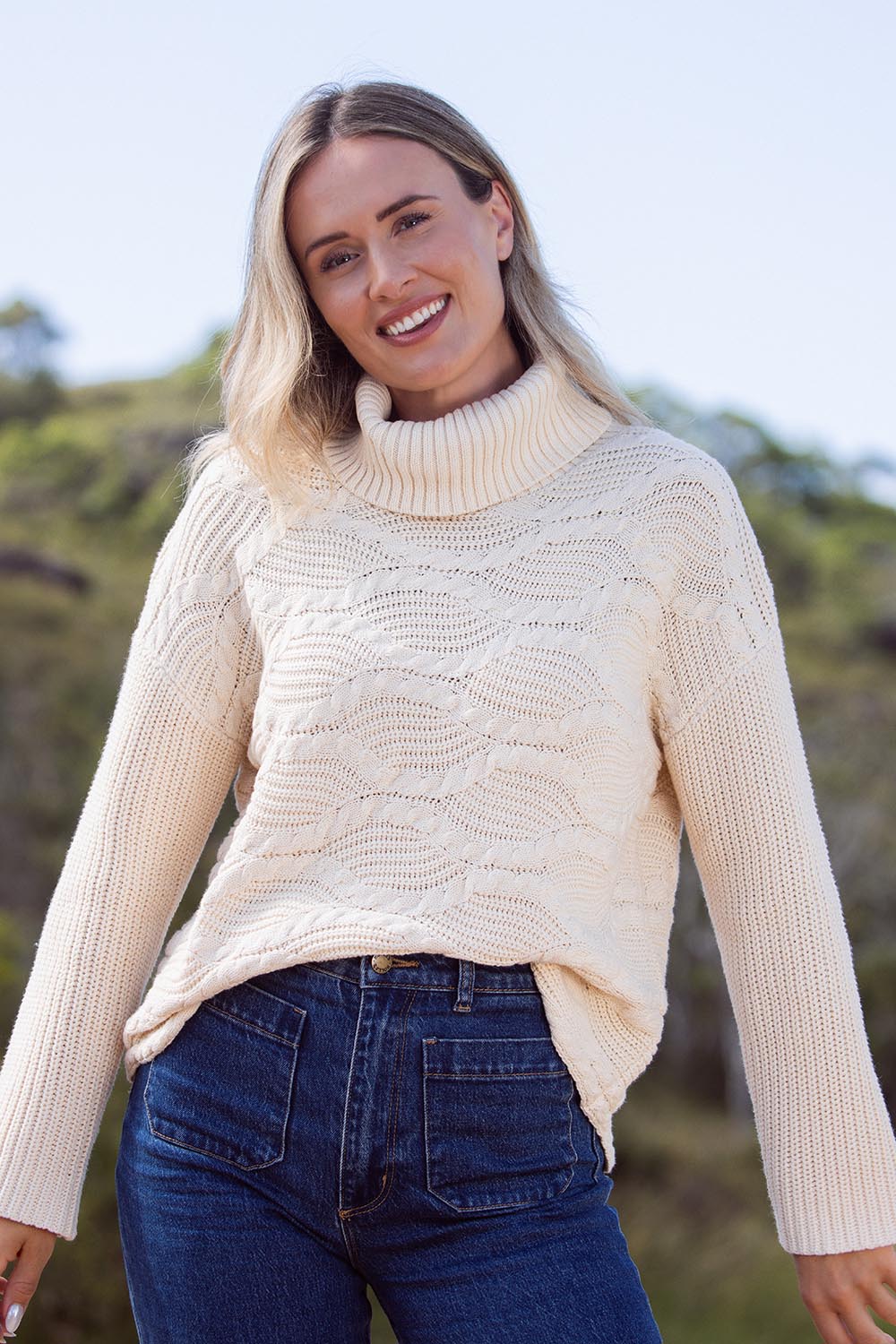 A model wearing the Wave Knit Roll Neck Cotton Blend Sweater in colour Vanilla, from the front, showing the whole outfit
