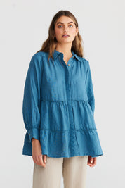 A model wearing the Mia Top in colour Bluesteel (Blue), from the front, cropped image