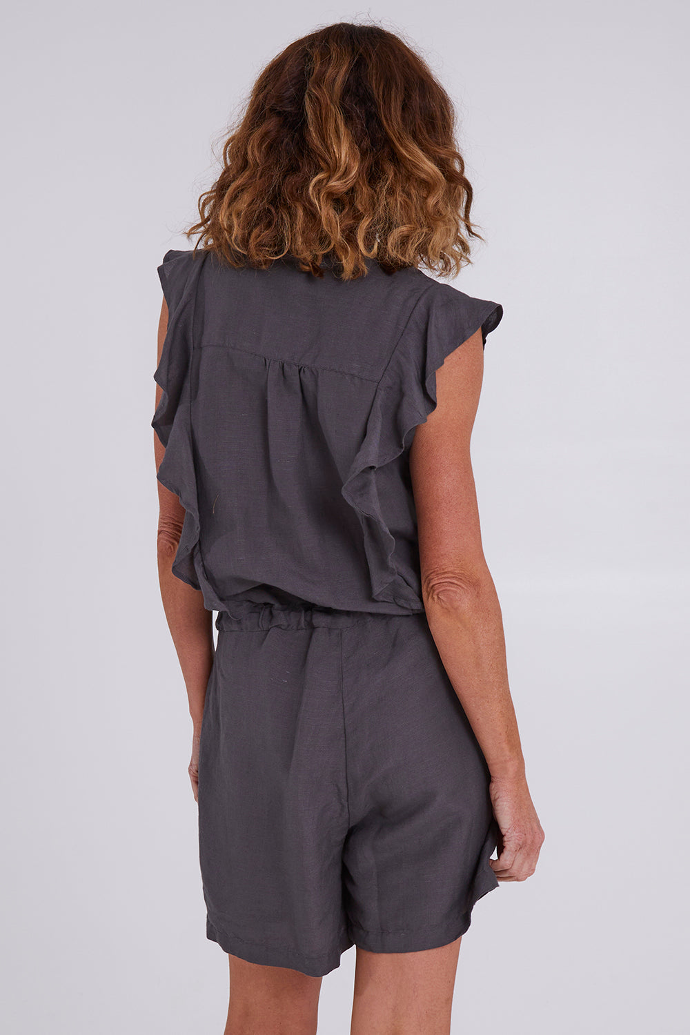 Model Emma wearing size S of the Mandalay Jumpsuit in colour Charcoal (Grey), from the back