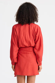 A model wearing the Porto Linen Dress in colour Cherry (Red), from the back