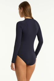 A model wearing the Long Sleeved Multifit One Piece in colour Nightsky (Blue), from the back