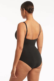 A model wearing the Eco Essentials Cross Front One Piece in colour Black (Black), from the back