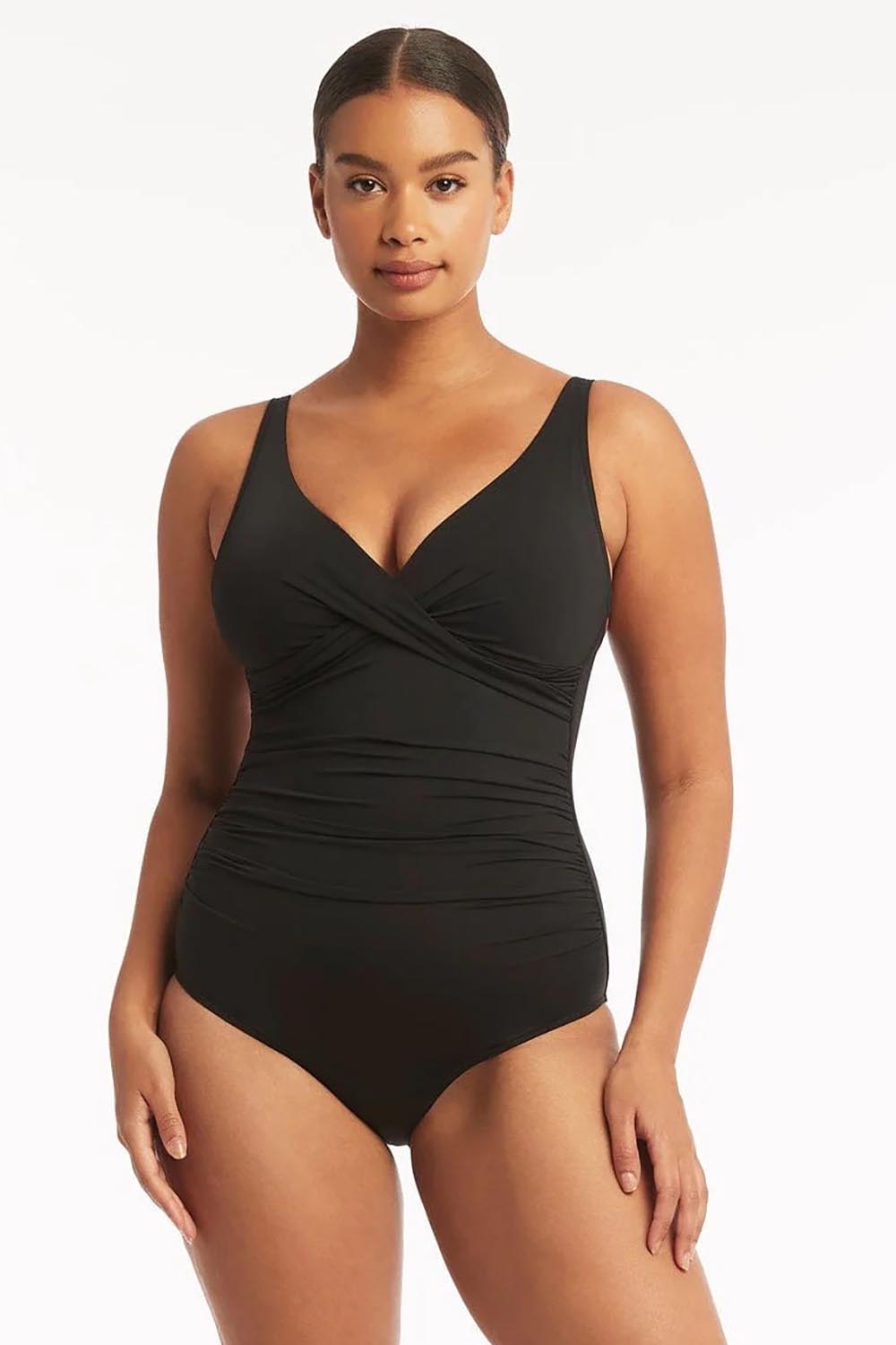 A model wearing the Eco Essentials Cross Front One Piece in colour Black (Black), from the front, cropped image