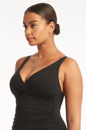 A model wearing the Eco Essentials Cross Front One Piece in colour Black (Black), from the front, cropped image