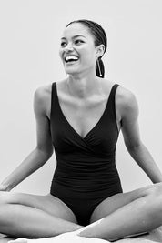 A model wearing the Eco Essentials Cross Front One Piece in colour Black (Black), from the front, showing the whole outfit