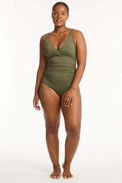 A model wearing the Eco Essentials Cross Front One Piece in colour Khaki (Green), from the front, showing the whole outfit