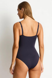 A model wearing the Eco Essentials Cross Front One Piece in colour Nightsky (Black), from the back