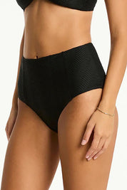 A model wearing the Panelled High Waist Pant in colour Black (Black), from the front, cropped image