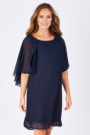 Model Emma wearing size 10 of the Butterfly Chiffon Dress in colour Navy (Blue), from the front, cropped image