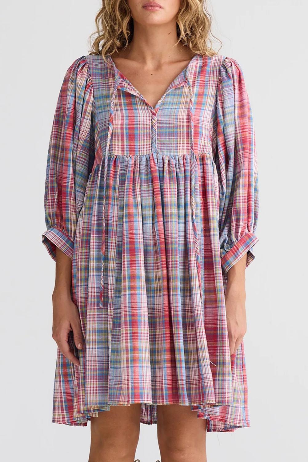 A model wearing the Winnie Cotton Mini Dress in colour Picnicchec (Pink), from the front, cropped image