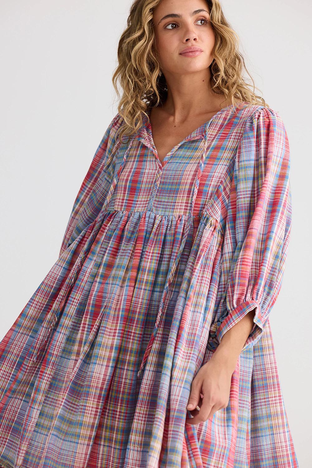 A model wearing the Winnie Cotton Mini Dress in colour Picnicchec (Pink), from the front, cropped image