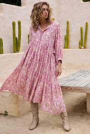 A model wearing the Wisteria Cotton Dress in colour Meadow (Pink), from the front, showing the whole outfit
