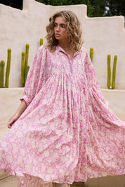 A model wearing the Wisteria Cotton Dress in colour Meadow (Pink), from the front, showing the whole outfit