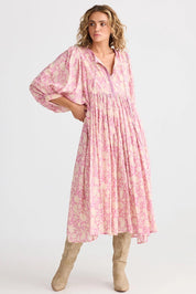 A model wearing the Wisteria Cotton Dress in colour Meadow (Pink), from the front, showing the whole outfit