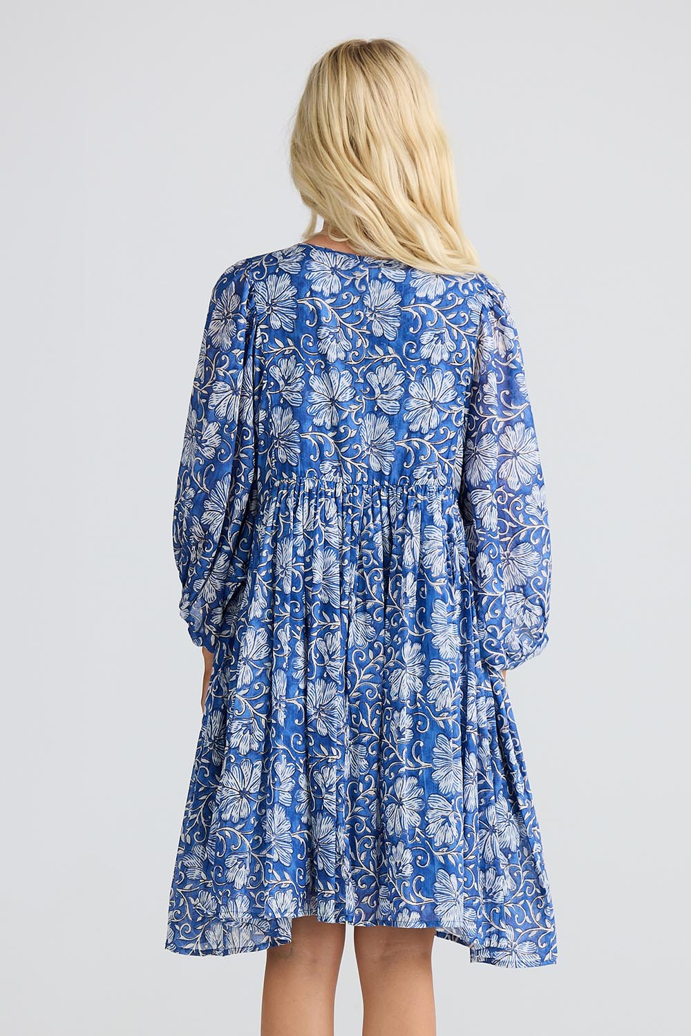 A model wearing the Wisteria Cotton Mini Dress in colour Blueblosso (Blue), from the back
