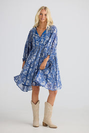 A model wearing the Wisteria Cotton Mini Dress in colour Blueblosso (Blue), from the front, showing the whole outfit