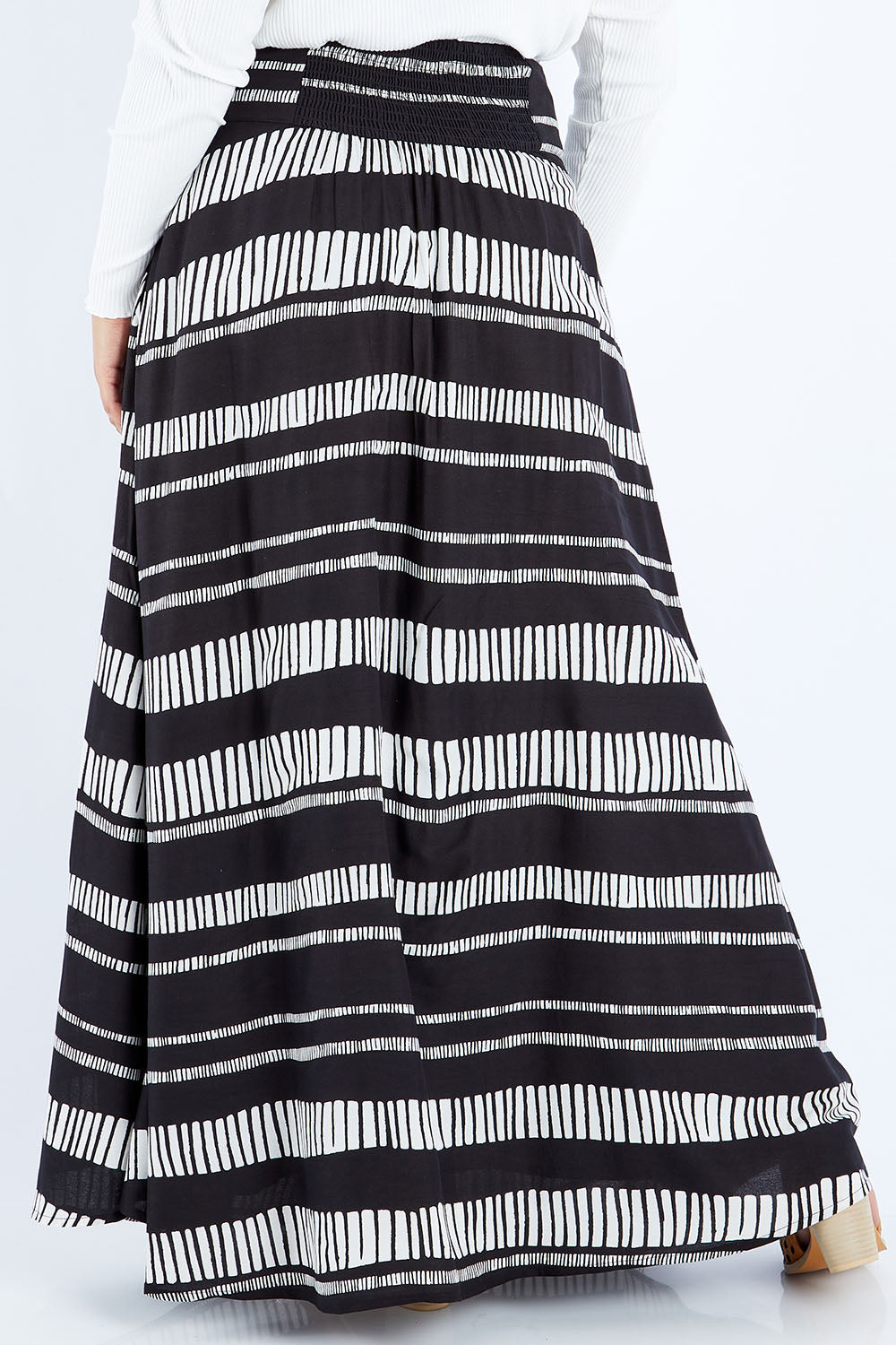 Model Sasha-Lee wearing size 16 of the Rosie Maxi Skirt in colour Sandstone (Black), from the back