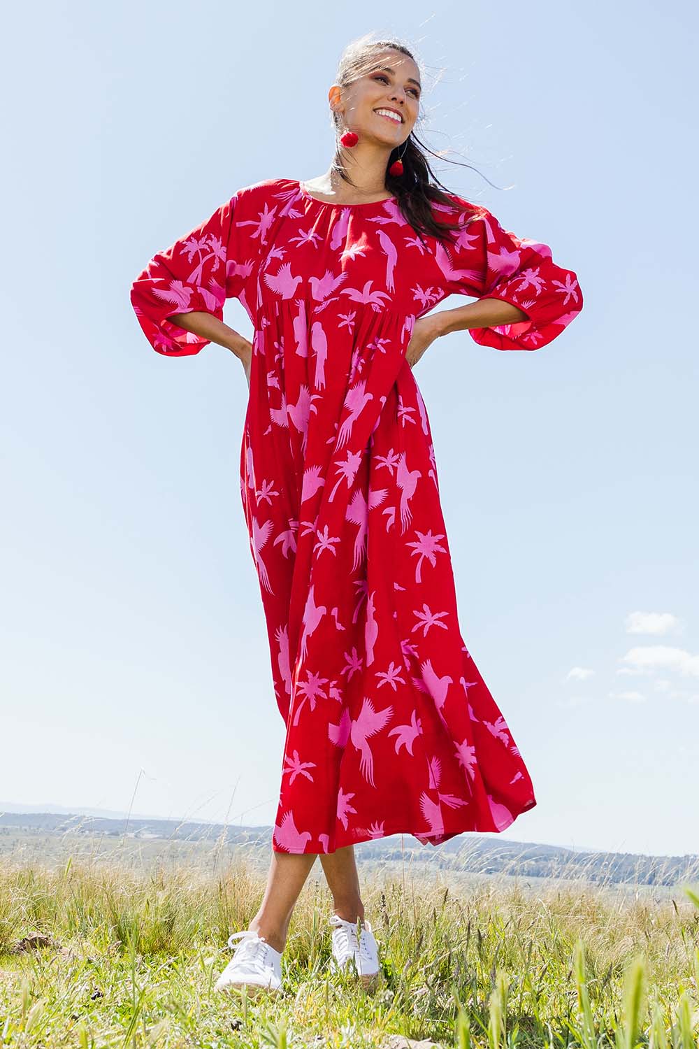Model Vitoria wearing size 10 of the Alice Gathered Dress in colour Bird (Red), from the front, showing the whole outfit
