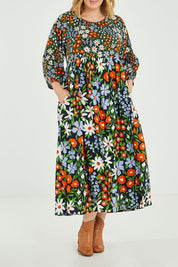 Model Jess wearing size 14 of the Alice Gathered Dress in colour Wildfield (Red), from the front, cropped image