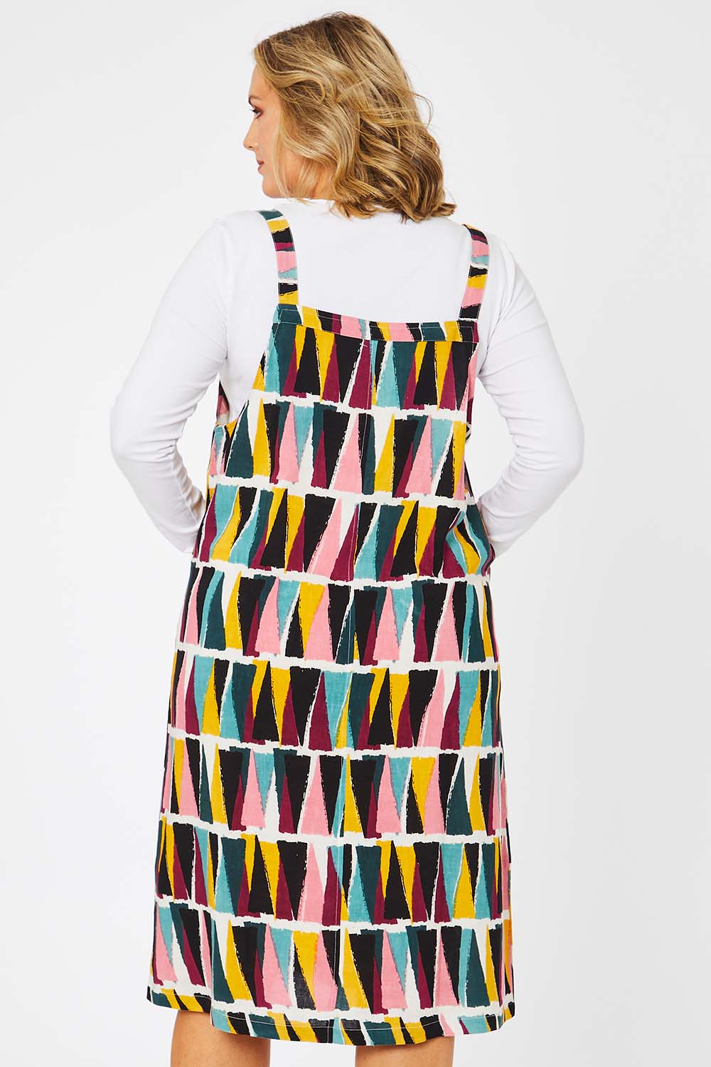 Model Jess wearing size 14 of the Charlotte A Line Pinafore Dress in colour Mountains (Blue), from the back