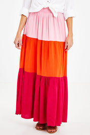 Model Courtney wearing size 10 of the Poppy Tier Skirt in colour Sunset (Pink), from the front, cropped image
