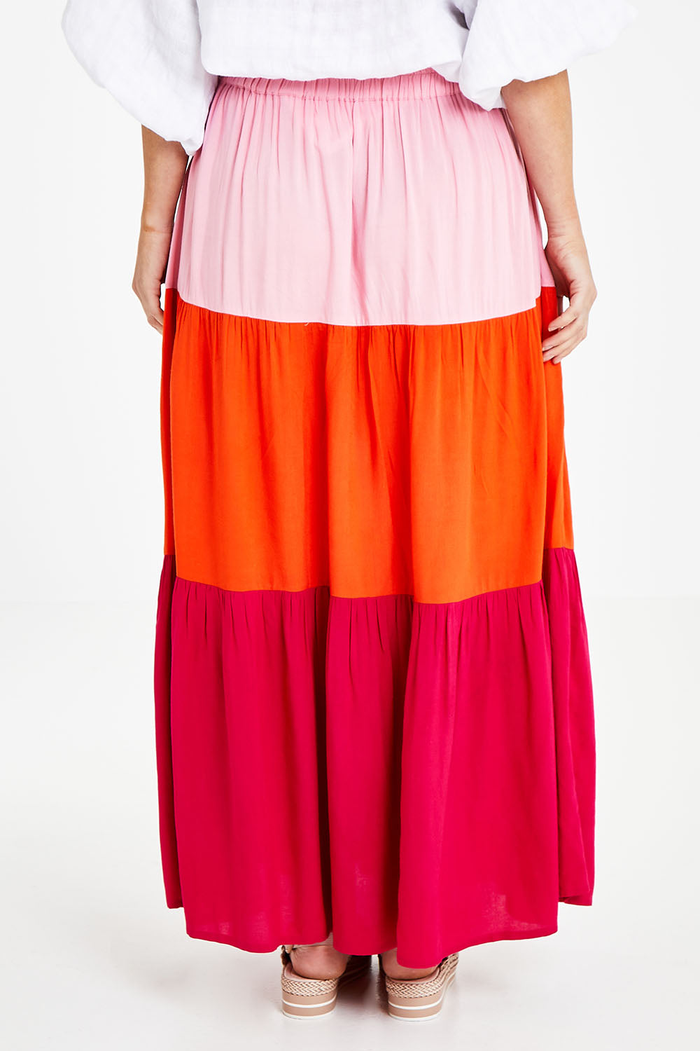 Model Laura wearing size 14 of the Poppy Tier Skirt in colour Sunset (Pink), from the back