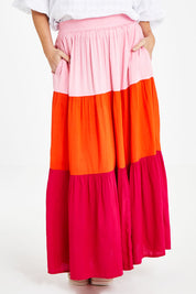 Model Laura wearing size 14 of the Poppy Tier Skirt in colour Sunset (Pink), from the front, cropped image