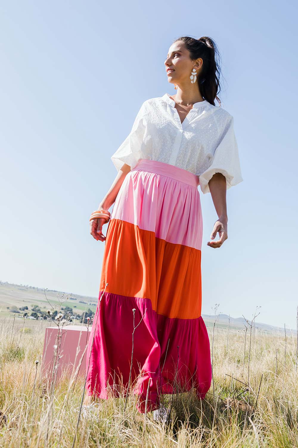 Model Vitoria wearing size 10 of the Poppy Tier Skirt in colour Sunset (Pink), from the front, showing the whole outfit