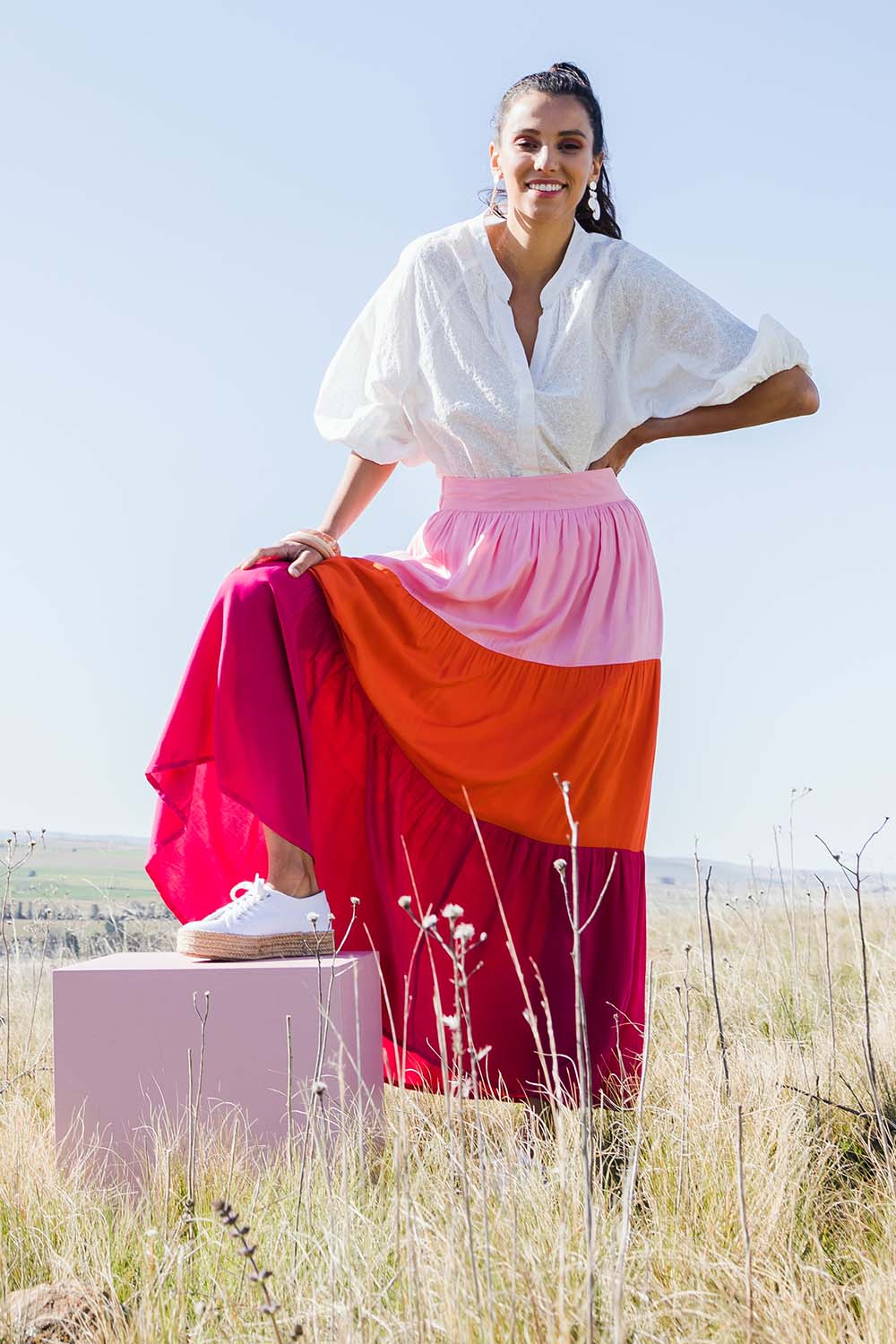 Model Vitoria wearing size 10 of the Poppy Tier Skirt in colour Sunset (Pink), from the front, showing the whole outfit
