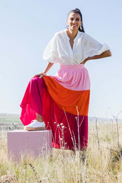 Model Vitoria wearing size 10 of the Poppy Tier Skirt in colour Sunset (Pink), from the front, showing the whole outfit