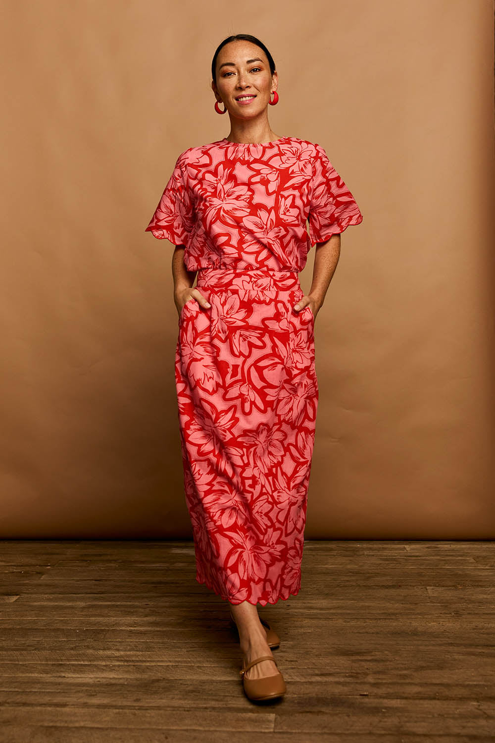 Model Katie wearing size 10 of the Valentina Cotton Scalloped Hem Top in colour Flowerpop (Red), from the front, showing the whole outfit