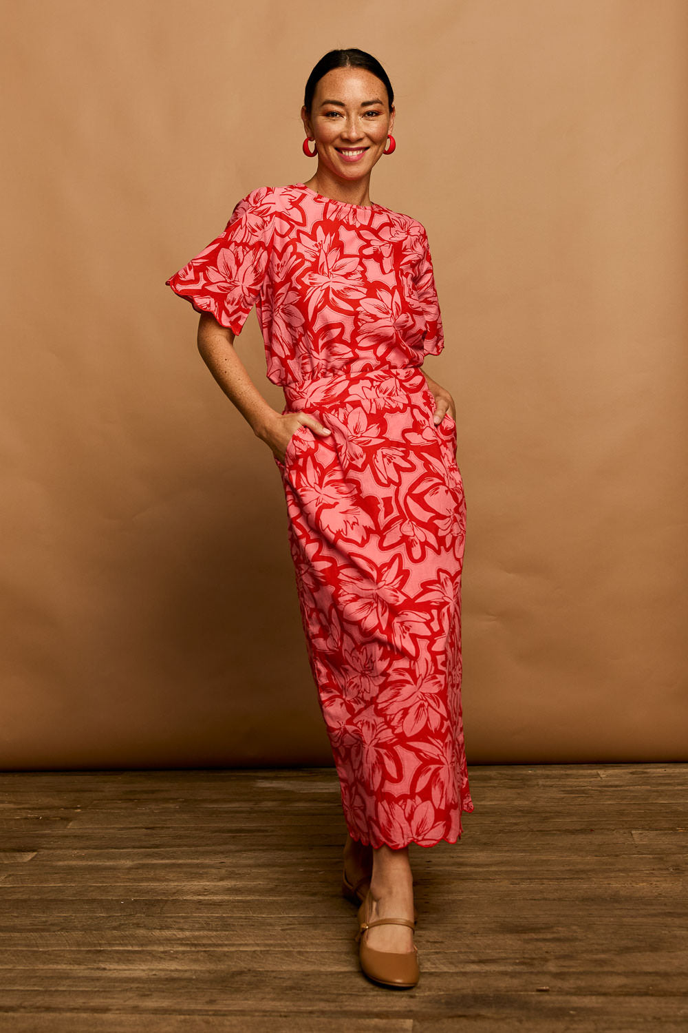 Model Katie wearing size 10 of the Camilla Cotton Scalloped Hem Skirt in colour Flowerpop (Red), from the front, showing the whole outfit