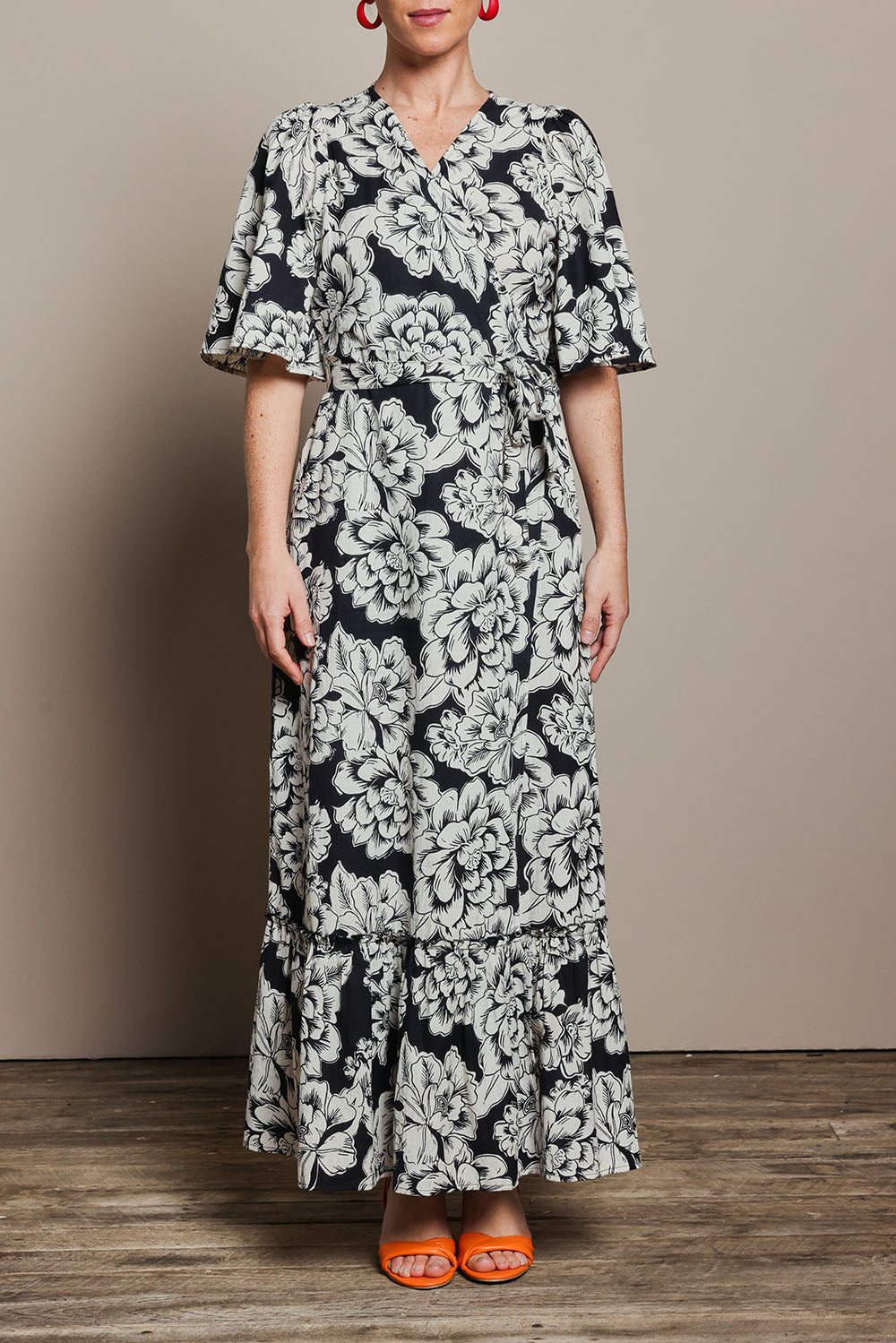Model Katie wearing size 10 of the Anastasia Cotton Wrap Dress in colour Blooming (Black), from the front, cropped image