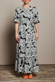 Model Katie wearing size 10 of the Anastasia Cotton Wrap Dress in colour Blooming (Black), from the front, cropped image