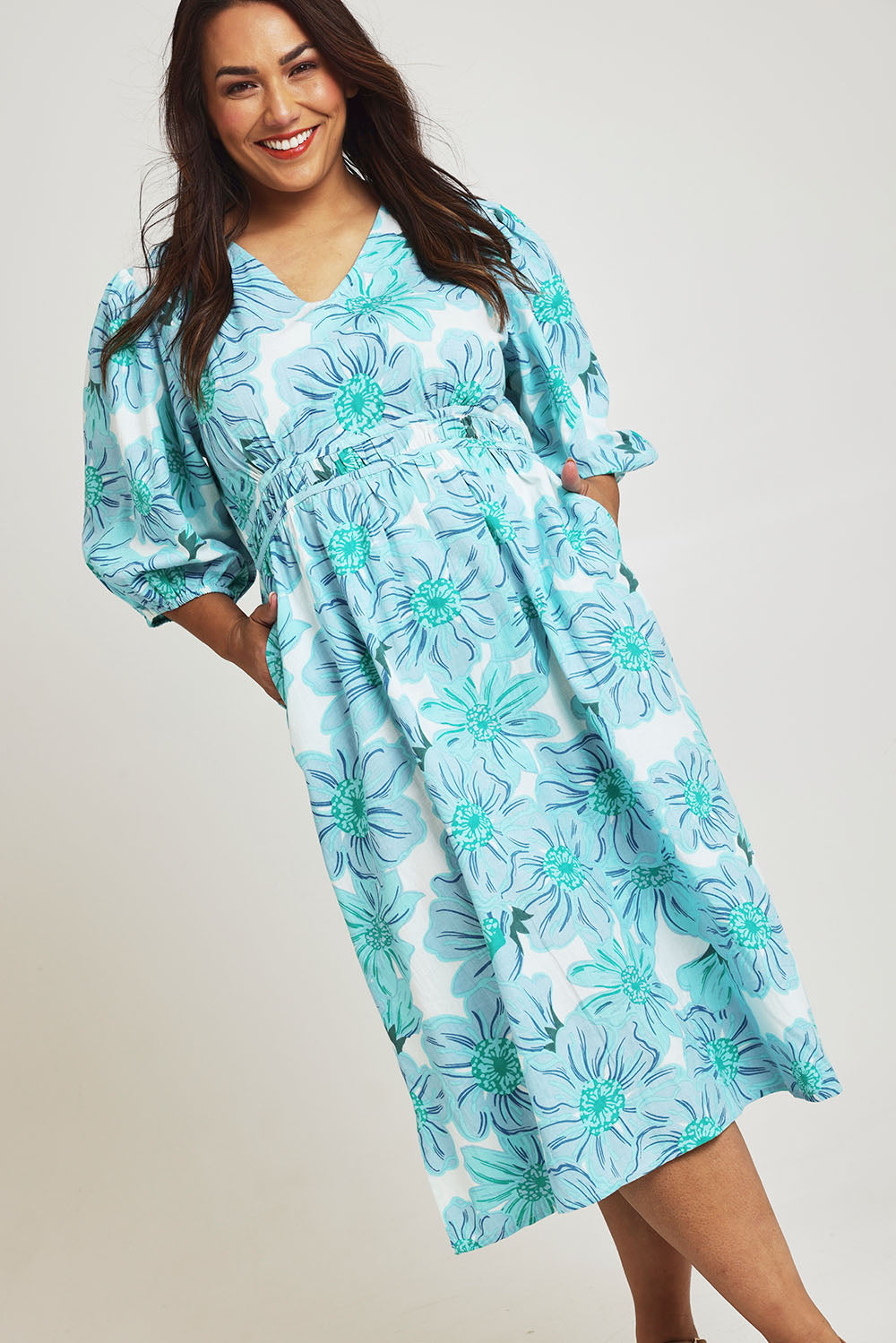 Model Ashleigh wearing size 16 of the Vivienne Cotton Dress in colour Rosettes (Blue), from the front, cropped image