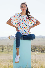 Model Vitoria wearing size 10 of the Lola Belle Sleeve Top in colour Speckled (White), from the front, showing the whole outfit