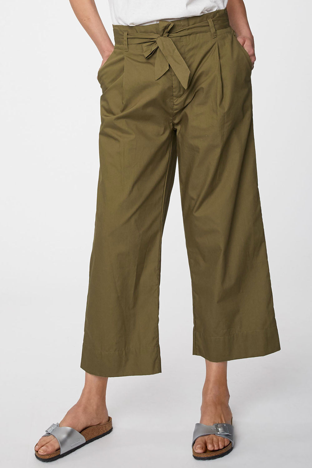A model wearing the Maddelena Trousers in colour Desert (Green), from the front, cropped image