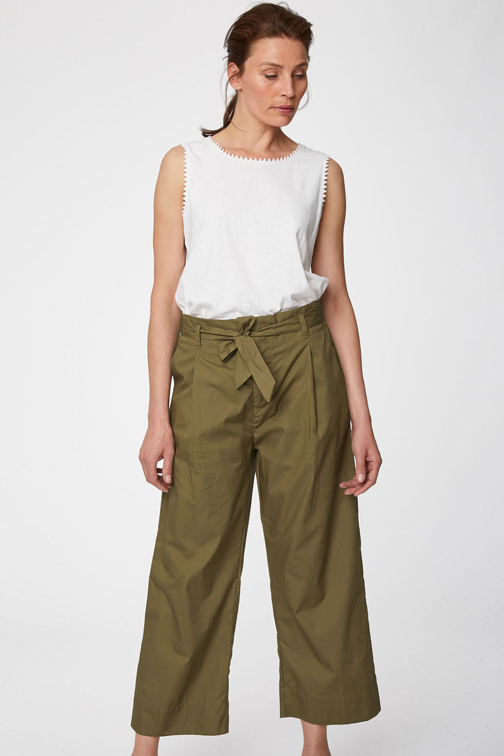 A model wearing the Maddelena Trousers in colour Desert (Green), from the front, cropped image