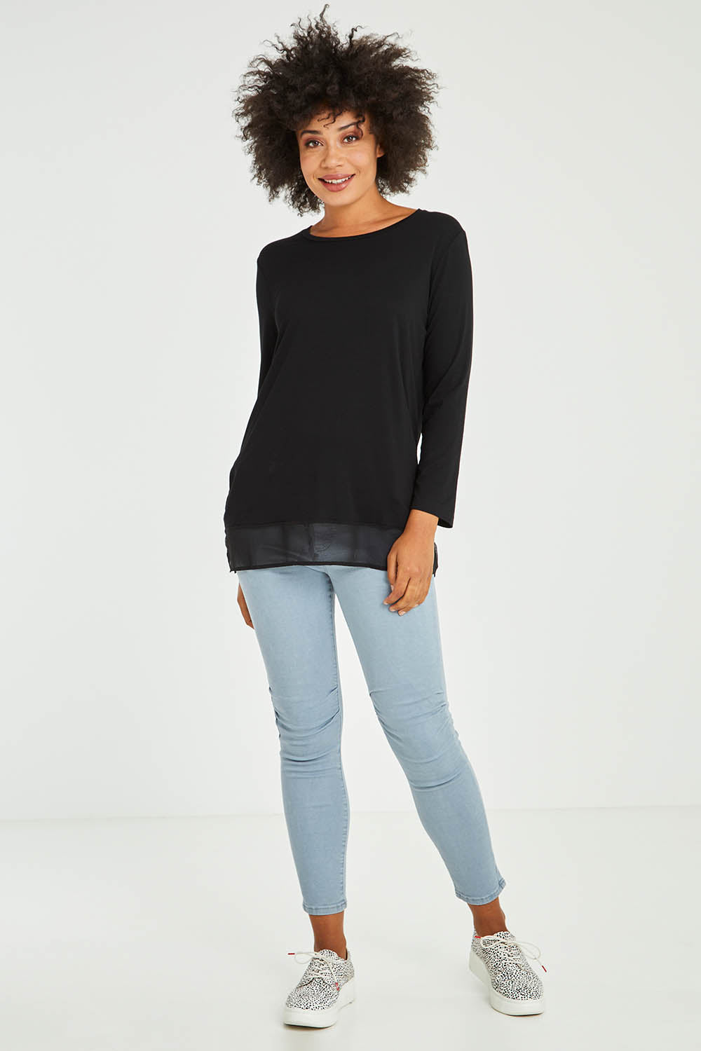 Model Olivia wearing size S of the L/S Georgette Hem Top in colour Black (Black), from the front, showing the whole outfit
