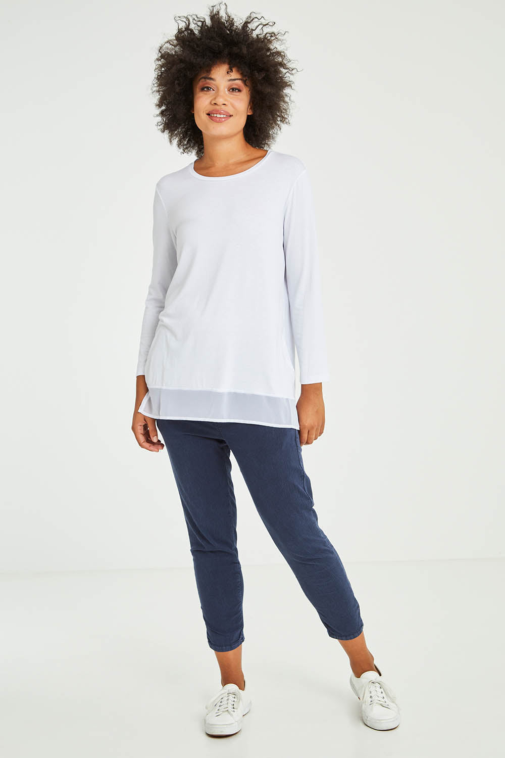 Model Olivia wearing size S of the L/S Georgette Hem Top in colour White (White), from the front, showing the whole outfit