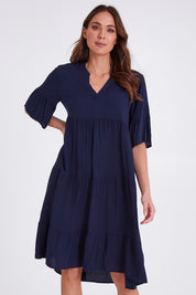 Model Madeline wearing size S of the Tier Swing Dress in colour Navy (Blue), from the front, cropped image