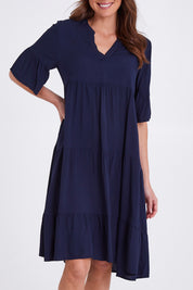 Model Madeline wearing size S of the Tier Swing Dress in colour Navy (Blue), from the front, cropped image