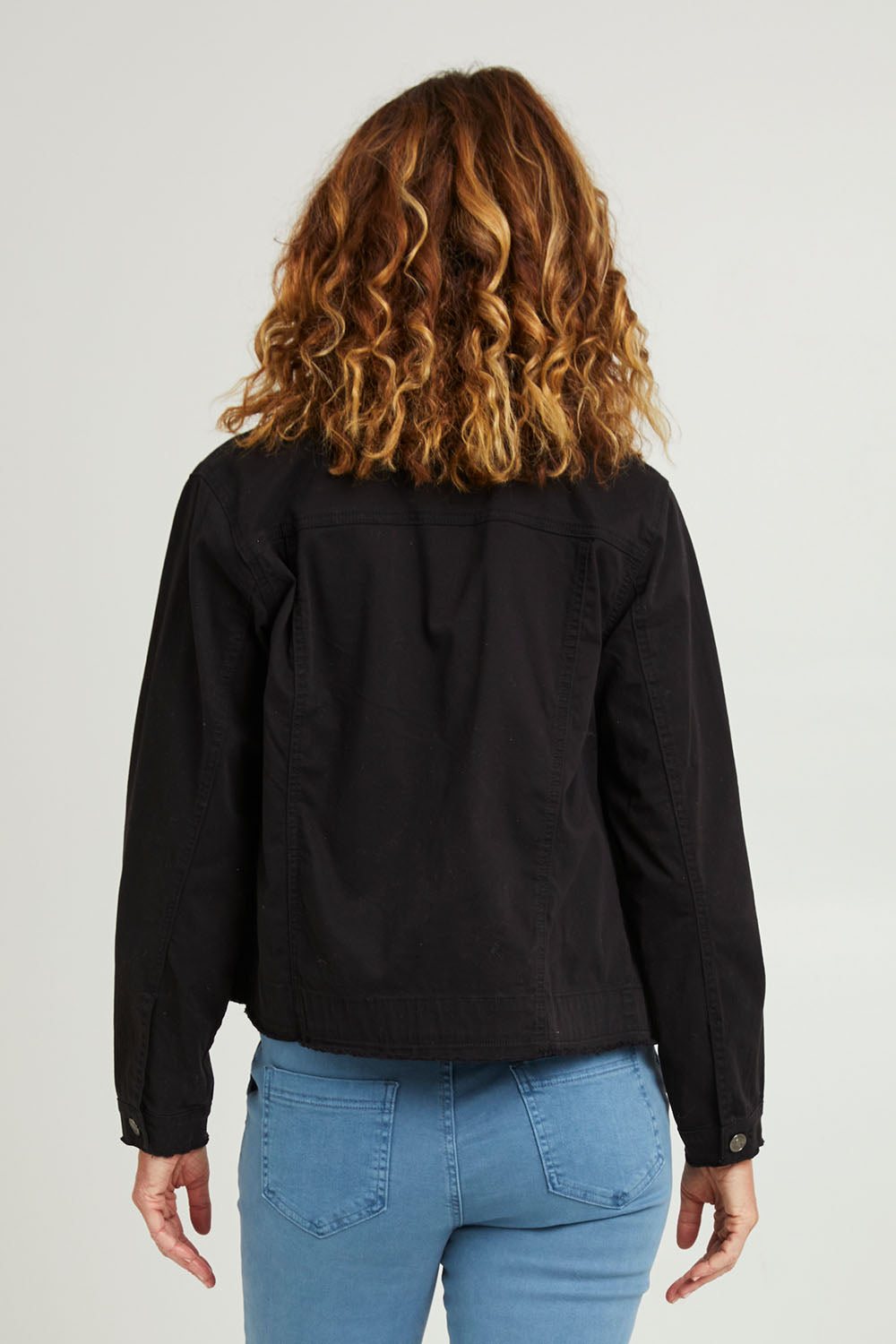 Model Emma wearing size S of the Collarless Denim Jacket in colour Black (Black), from the back