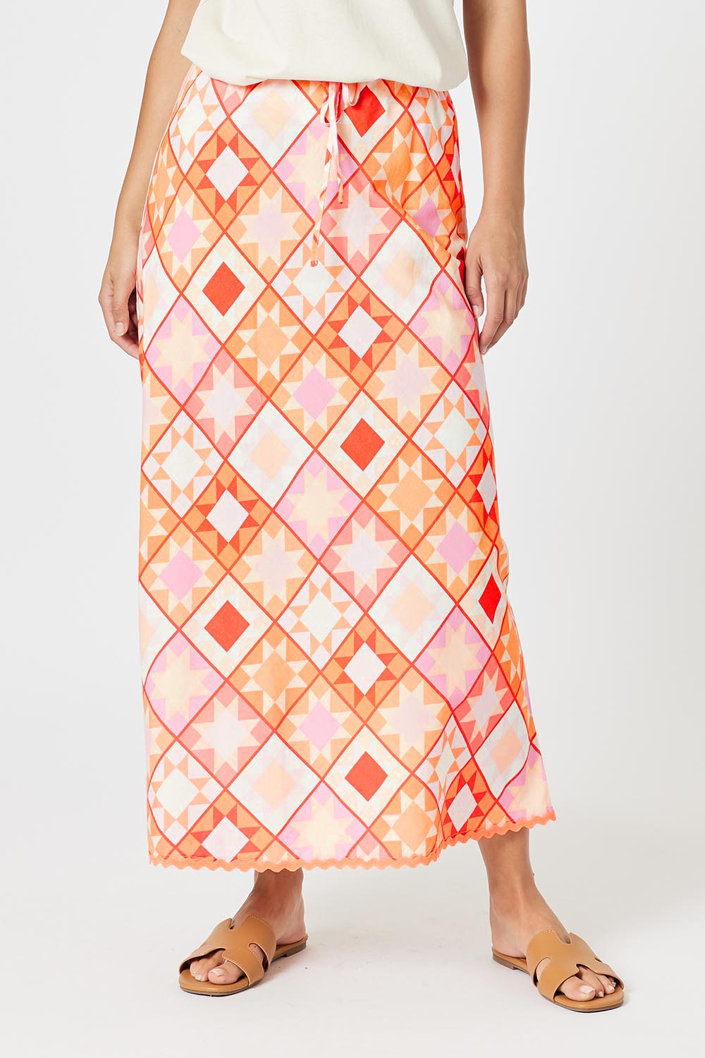 A model wearing the Corfu Print Linen Blend Skirt in colour Mango, from the front, cropped image