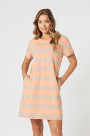 A model wearing the Love & Kisses Cotton Dress in colour Mango, from the front, cropped image