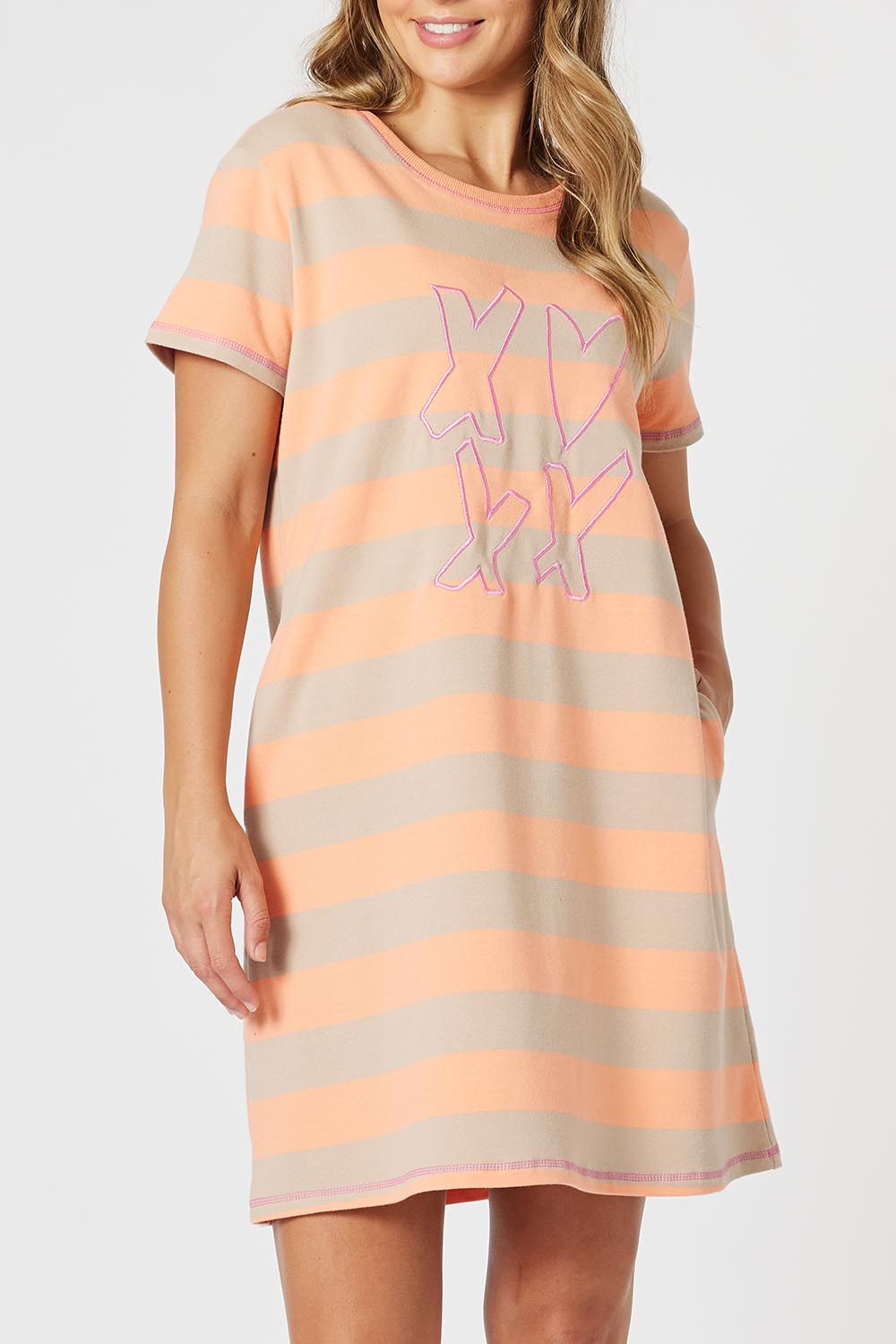A model wearing the Love & Kisses Cotton Dress in colour Mango, from the front, cropped image