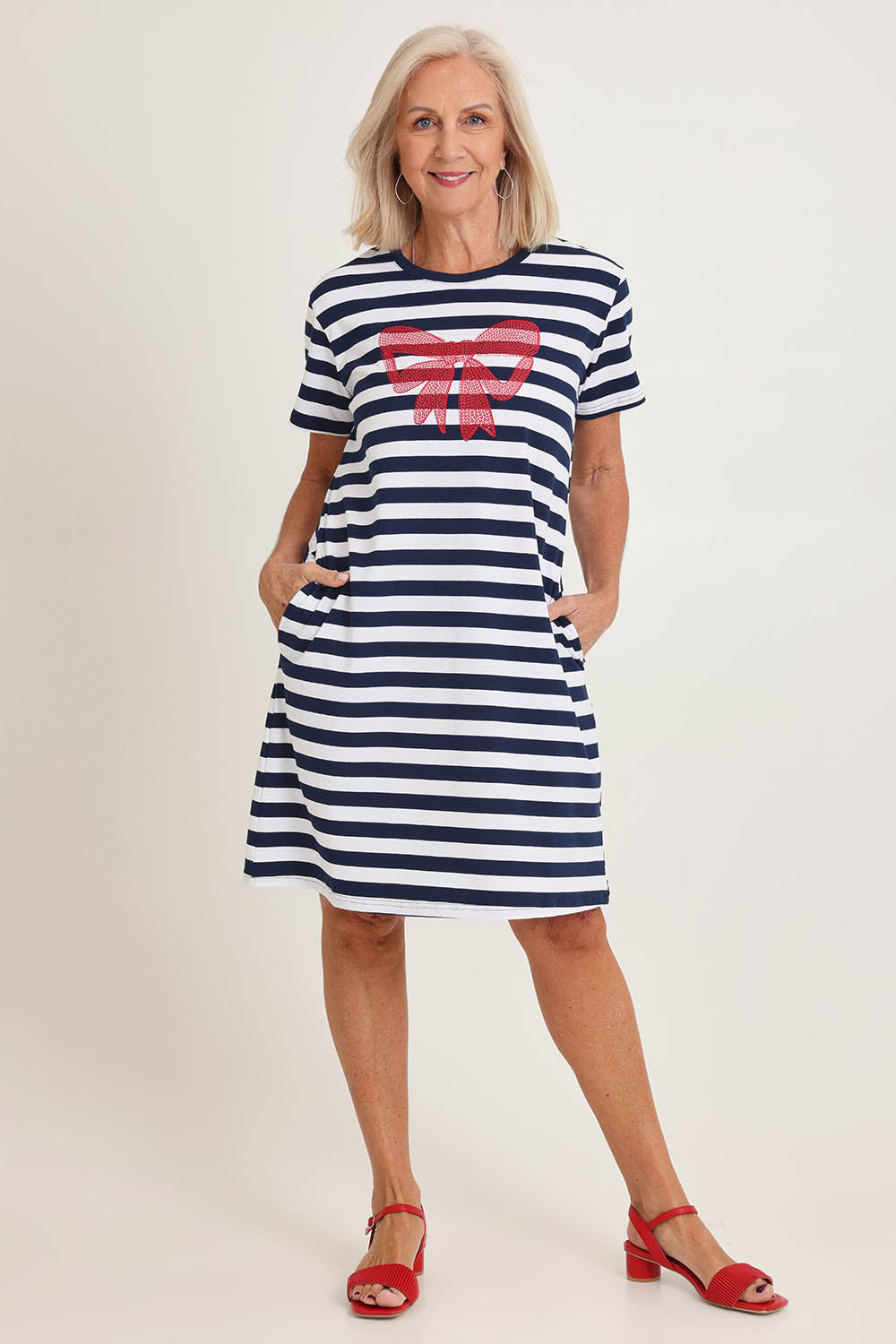 Model Sandy wearing size S of the Red Bow Stripe Cotton Dress in colour Navy (Blue), from the front, showing the whole outfit