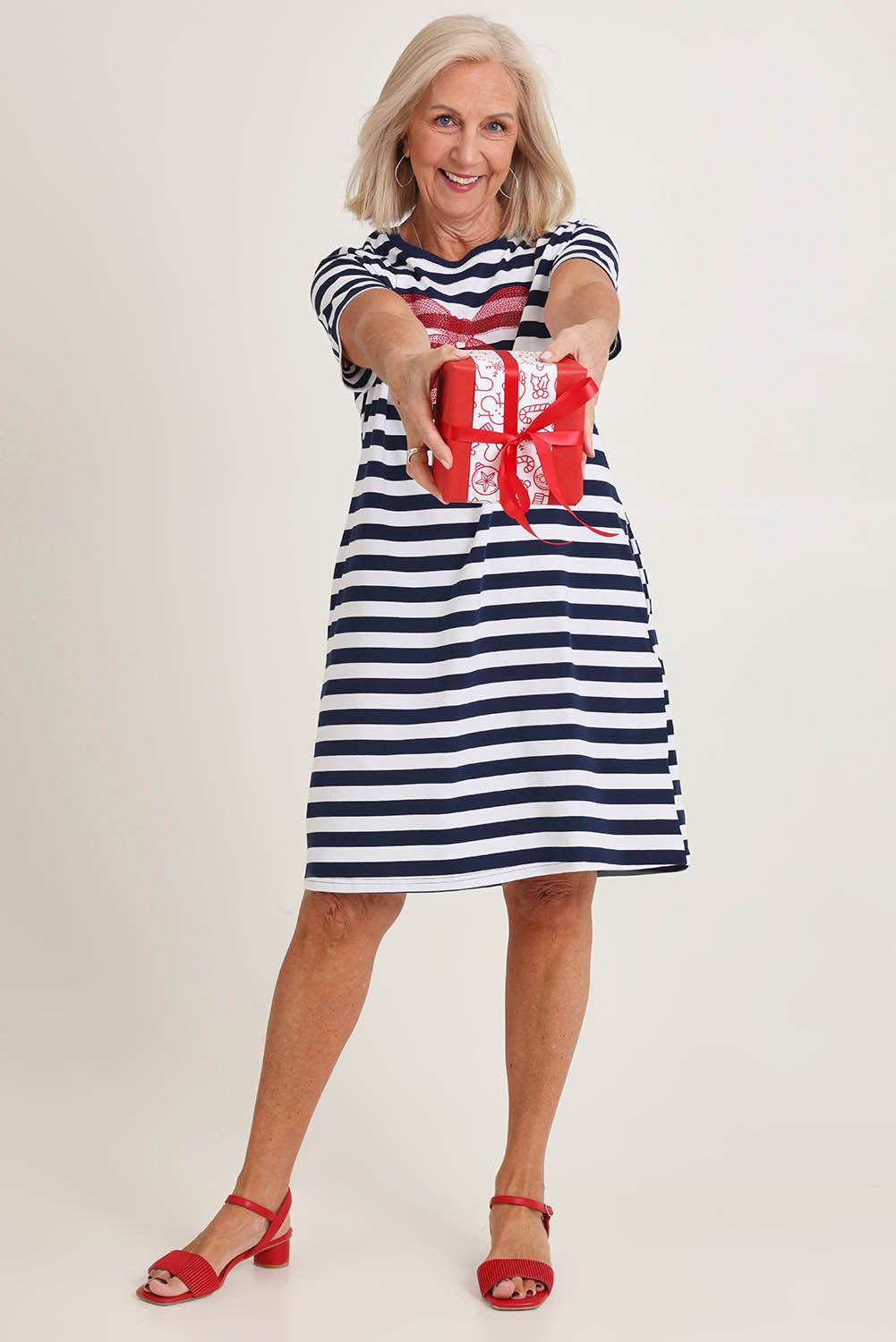 Model Sandy wearing size S of the Red Bow Stripe Cotton Dress in colour Navy (Blue), from the front, showing the whole outfit