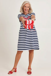 Model Sandy wearing size S of the Red Bow Stripe Cotton Dress in colour Navy (Blue), from the front, showing the whole outfit